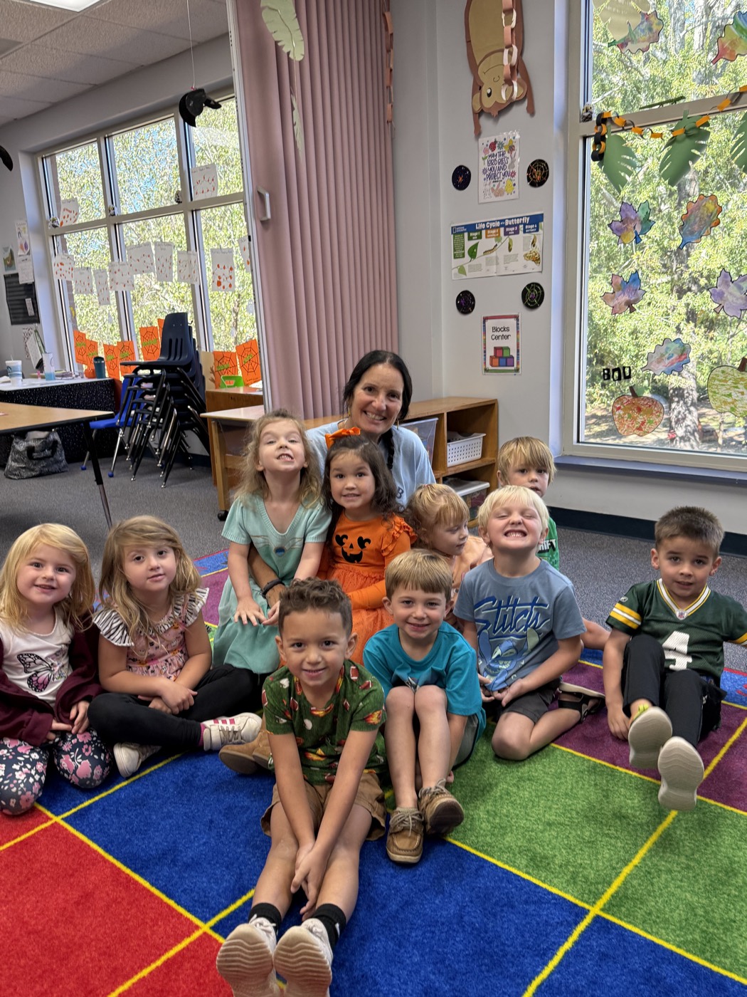 A Mt. Horeb Preschool class and their teacher sitting together on the classroom rug