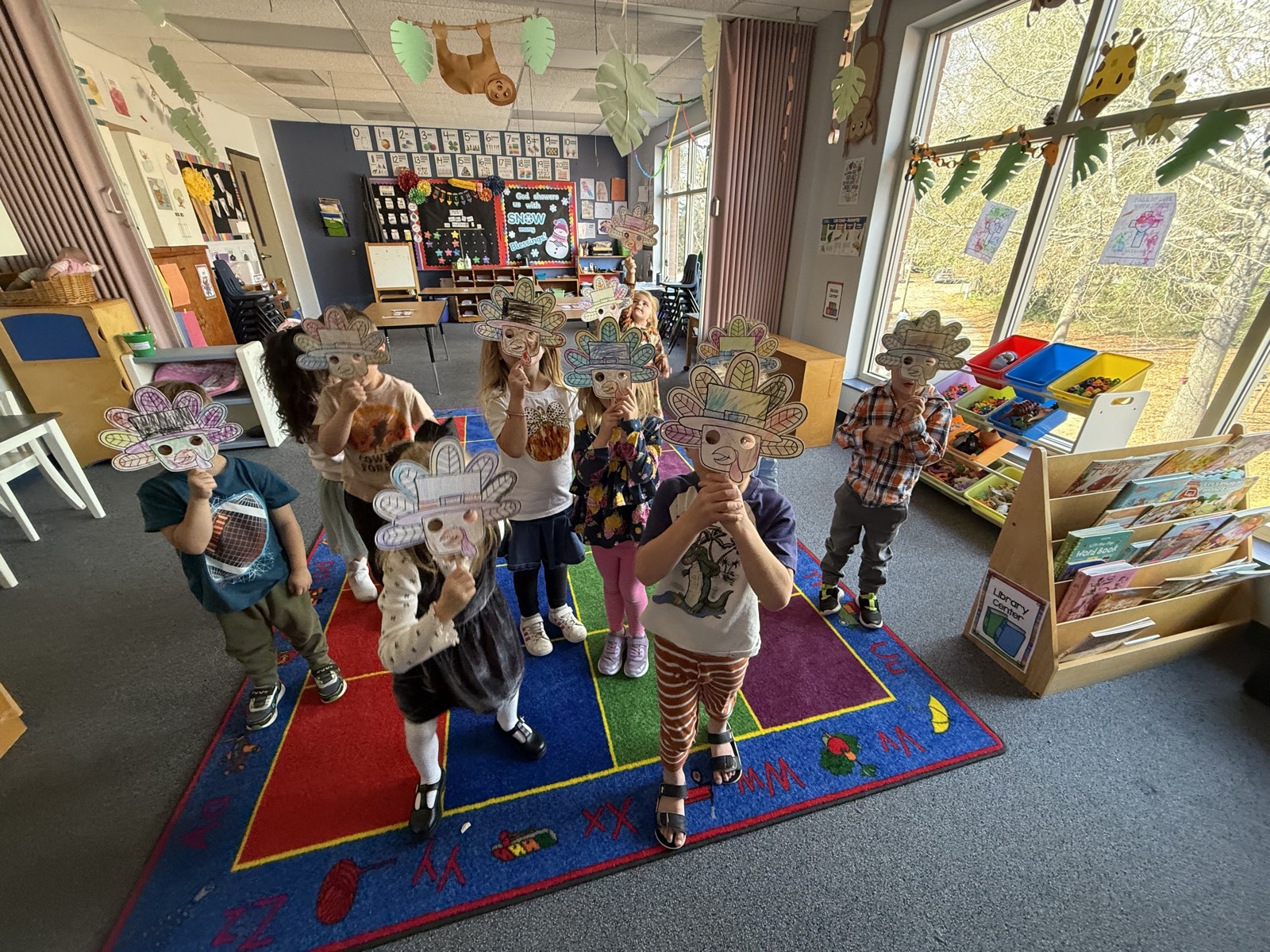 Mt. Horeb preschoolers holding up paper masks they made, in a bright classroom with a reading corner